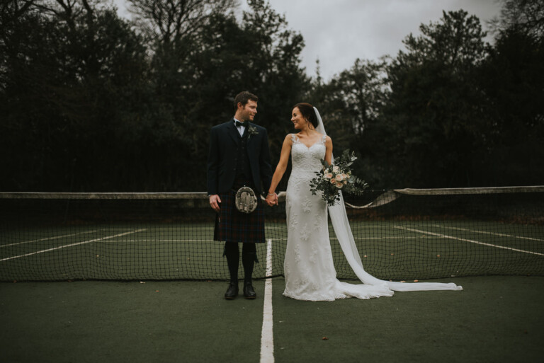 Bride and groom on the tennis court holding hands