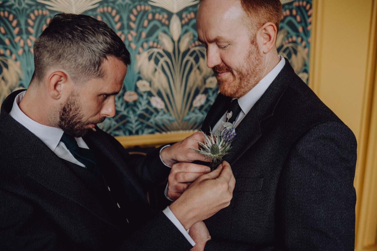 Groom helping best man with his button hole